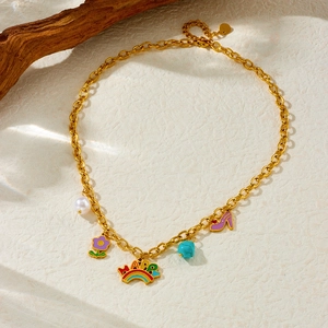 Detail of gold necklace featuring rainbow happy charm, purple flower and blue turquoise pendant