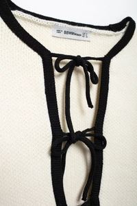 Détail de la bordure contrastée et de l'étiquette de taille sur le cardigan en maille