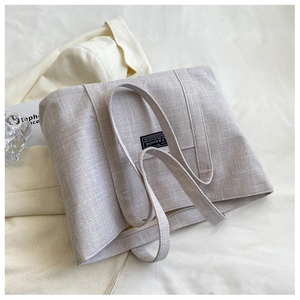 Detail of grey canvas tote bag with fashion label and textured fabric material