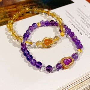Detail of beaded bracelets with citrine stones and gold gourd charms in vintage style