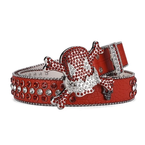 Detailed view of red crocodile texture belt with sparkling skull buckle and rhinestones