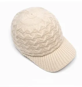 Close-up of cream knit baseball cap showing cable stitch pattern and warm wool texture