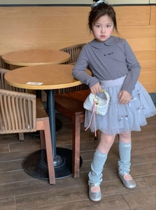 Model showcasing a grey Peter Pan collar top with a tutu skirt and white mini handbag