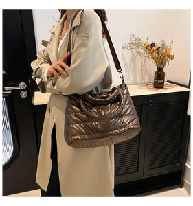 Detail of metallic quilted puffer tote bag with wide strap worn with trench coat