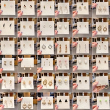 Macro close-up display of 36 pairs of vintage style metal earrings with pearls and crystals