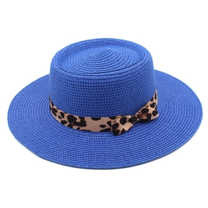 Detail of blue woven sun hat with leopard print ribbon and bow on a white background