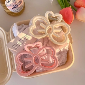 Macro view of cream and pink matte bow hair clips in a gift box with a metal spring