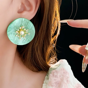 Details von übergroßen mintgrünen Harzohrringen mit Zirkon und Perleneinsätzen am Model