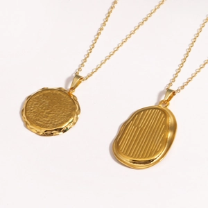 Detail view of two gold titanium steel necklaces with textured round and oval pendants