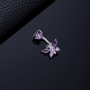 Close-up of double purple zircon butterfly belly ring on black reflective surface