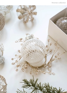 Vue détaillée d'une boule de Noël blanche à texture quadrillée sur un support doré