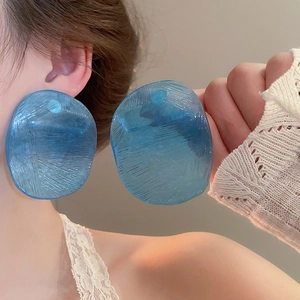 Close-up of translucent blue irregular resin earrings with ice texture on model
