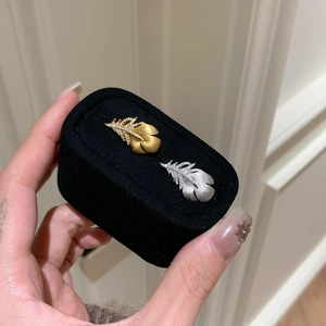 Luxurious gold and silver feather brooches with pavé zircon stones in a velvet box