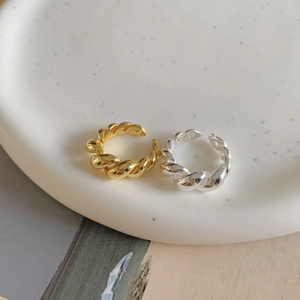 Detail of gold and silver S925 sterling silver twisted rope open rings on a ceramic plate