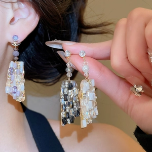 Detail of luxury geometric earrings with crystals and pearls in purple, black, and white
