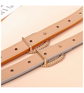 Detail of light brown leather belts with decorative gold buckles and pearl accents