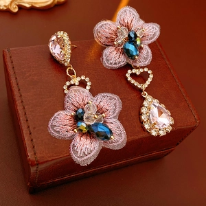 Detailed macro of vintage asymmetrical pink embroidery flower earrings with waterdrop gems