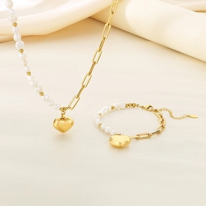 Ensemble élégant collier pendentif cœur doré et bracelet perles sur tissu beige