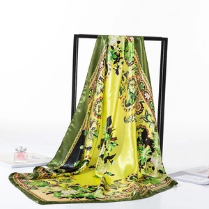 Elegant green silk scarf with floral paisley patterns draped on a black frame