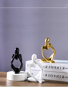 Close-up of abstract thinker resin sculptures in gold, black, and white matte finish