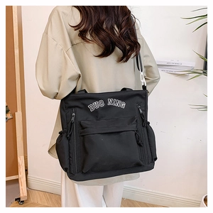 Detail of black canvas tote bag with DUO NING lettering and functional side pockets