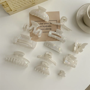 Iridescent mermaid PVC hair claw clips in various shapes on a clean white desk