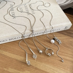 Detailed view of silver snake chains with tiger eye and pearl pendants on a book