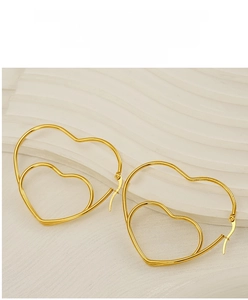 Detail of gold double-layered heart hoop earrings on a minimalist white textured backdrop