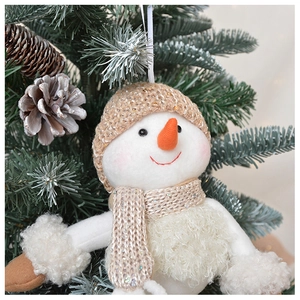 Detail of plush snowman ornament with sequined knit hat hanging on a Christmas tree