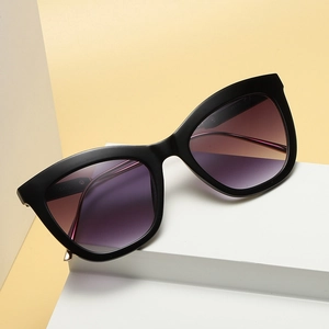 Stylish black cat-eye sunglasses with purple gradient lenses on a minimalist stand