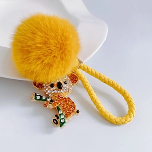 Detail of yellow koala keychain featuring fuzzy pompom and rhinestone encrusted metal charm