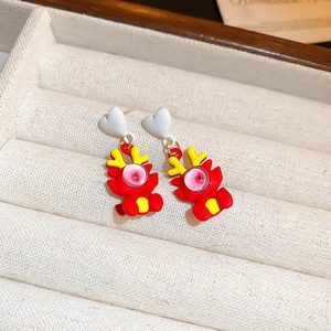 Détail de boucles d'oreilles dragon rouge avec clous en cœur sur plateau à bijoux