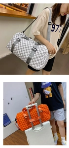 Large capacity checkered travel duffle bag shown carried and on a suitcase trolley