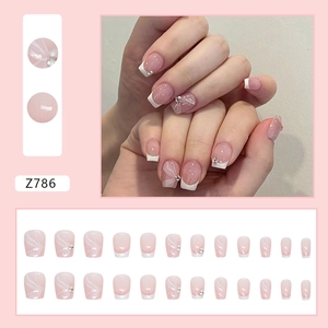 Pink and white French press-on nails with ribbon patterns and pearl decorations