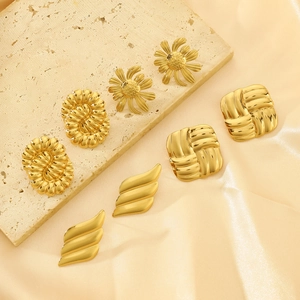 Detailed view of assorted gold plated stud earrings set on elegant silk fabric
