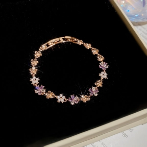 Detailed view of rose gold flower bracelet with purple crystals and pearls in a velvet box