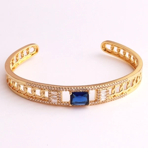 Detail of gold open bracelet featuring rectangle blue gemstone and zircon chain design