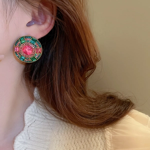 Close-up of vintage gold earrings with radiating pink and emerald green crystals