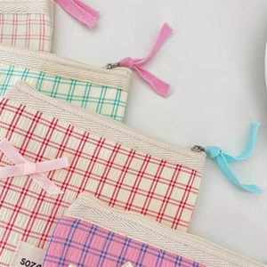 Detail of plaid toiletry bags with ribbon bows and sturdy metal zippers for storage