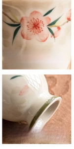 Detail of hand-painted pink peach blossoms on a ceramic teacup with a stable flat base