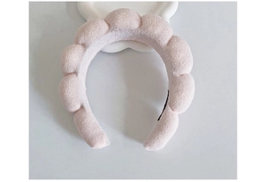 Macro shot of a pink plush cloud-shaped headband on a clean white display tray
