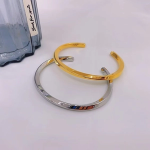 Polished Mobius twist open bracelets in gold and silver finish on white background