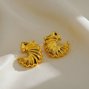 Macro shot of gold-plated shell textured earrings on a white silk background