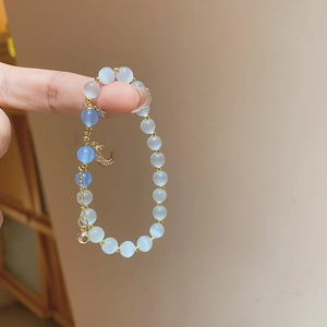 Detail of beaded bracelet with cat eye stones and a gold-plated crescent moon charm