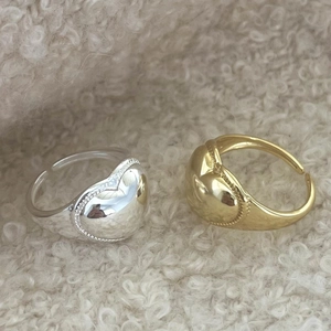 Macro detail of polished heart rings in gold and silver finish on soft texture