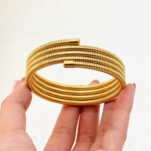 Close-up of golden spring coil bracelet featuring multi-layered stainless steel spiral design