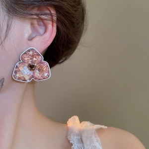 Detailansicht eines rosa Kristallblumen-Ohrrings mit silberner Seilstruktur an einem Model