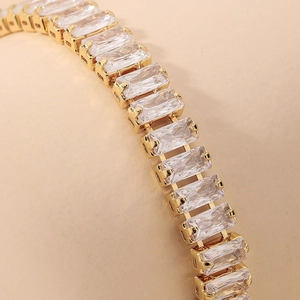 Macro shot of gold tennis bracelet featuring emerald-cut cubic zirconia in four-prong settings