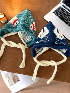 Detailed knit of handmade balaclava featuring sheep pattern on wooden desk layout