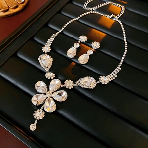 Macro view of silver floral rhinestone necklace and teardrop earrings on black velvet